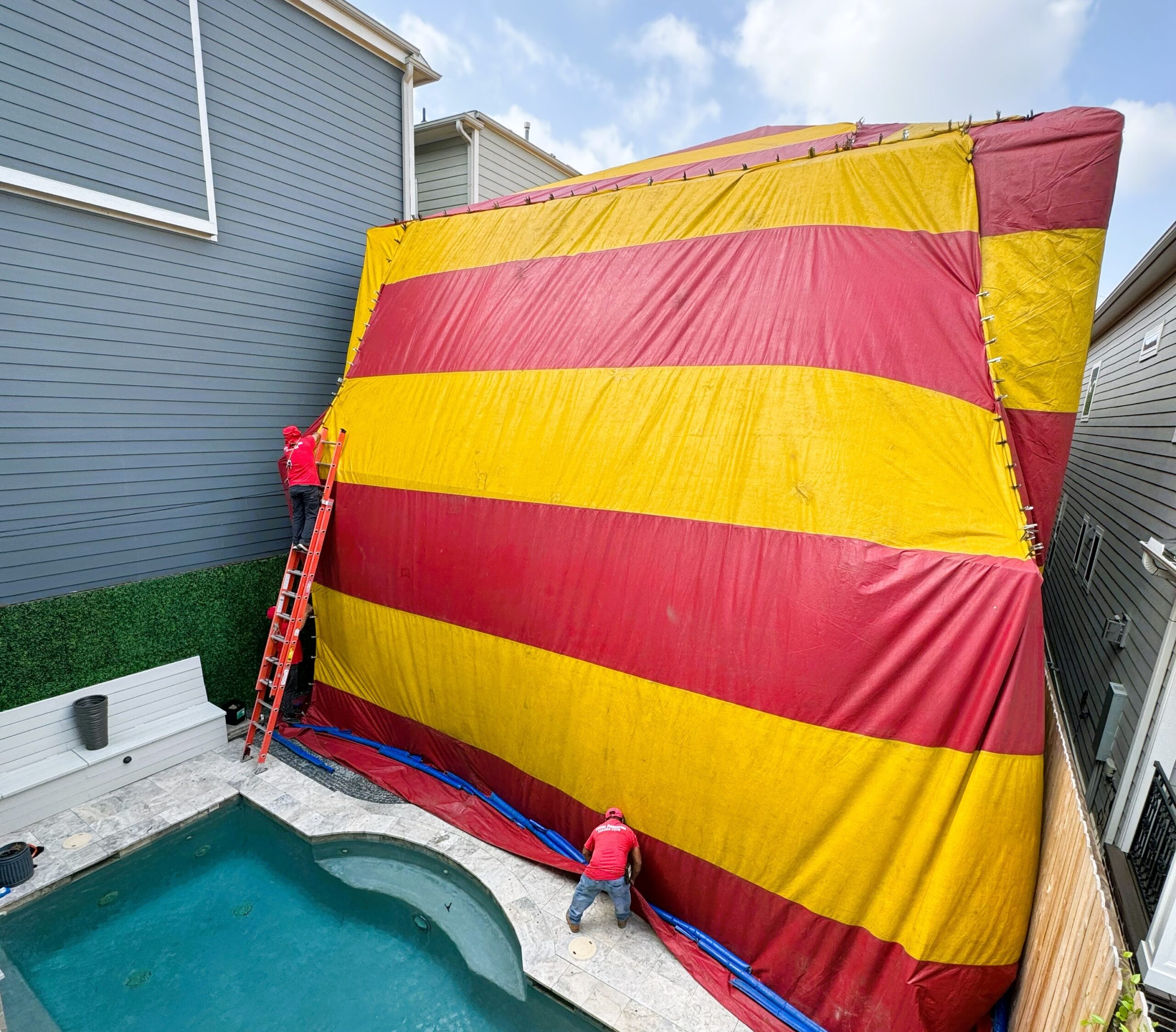 Yellow and red fumigation tent covering the back of a home that has a pool